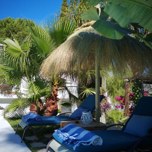 two blue lounge chairs under a straw umbrella at Casa Silca in Marbella