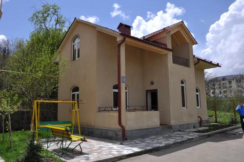 a small yellow house with a playground in front of it at Alpina Resort by Stellar Hotels, Tsaghkadzor in Tsaghkadzor