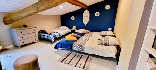 um quarto com 2 camas e uma parede azul em Gîte des écuries de la paguere em Aurignac