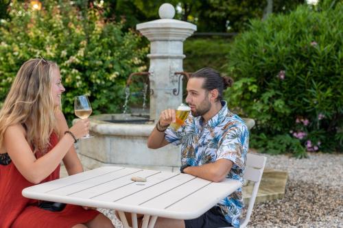 a man and woman sitting at a table drinking wine at Camping RCN La Bastide en Ardèche in Sampzon