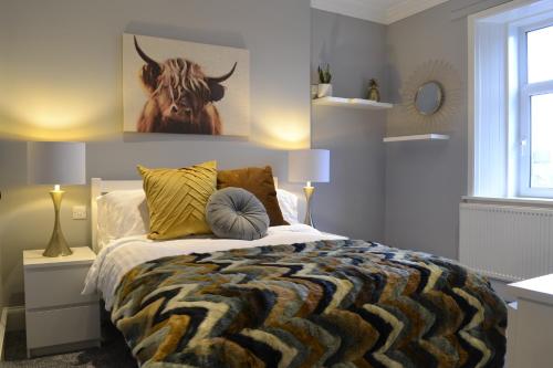 a bedroom with a bed with a bull painting on the wall at Stunning Period Townhouse with Garden, Walking Distance to Town in Dumfries