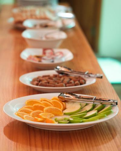 Burulu Inn في Gaafaru: طاولة خشبية عليها أطباق من الفاكهة والمكسرات