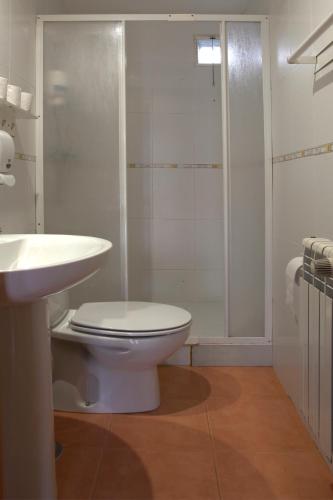 a white bathroom with a toilet and a shower at Apartamentos El Campal in Felechosa
