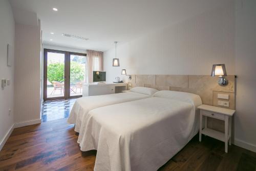 Un dormitorio con una gran cama blanca y un balcón. en Hotel Rural El Molino de Felipe, en Mula
