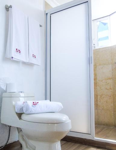 a white bathroom with a toilet and a shower at Ma Petite Maison in Tepoztlán
