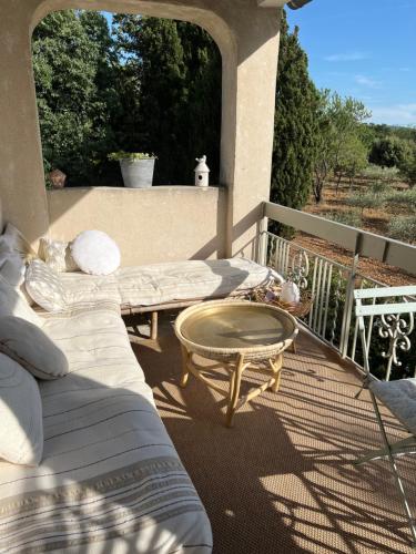a patio with a couch and a table on a balcony at Mas Coeur Provence Calme Beauté Grand Parc in Pernes-les-Fontaines
