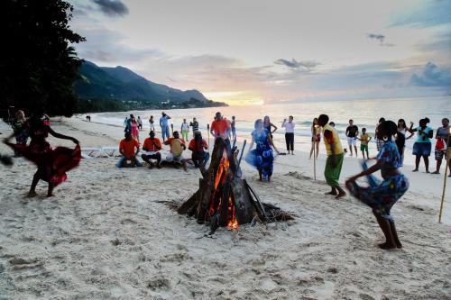 a group of people playing around a bonfire on the beach at Coral Strand Smart Choice in Beau Vallon