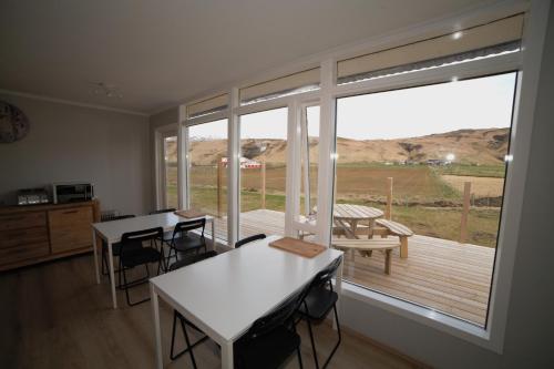 una stanza con tavolo e sedie e una grande finestra di Guesthouse Skógafoss a Skogar