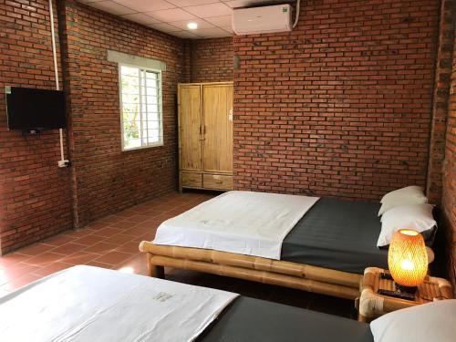 a bedroom with two beds and a brick wall at Nguyet Que Homestay & Tours in Ben Tre