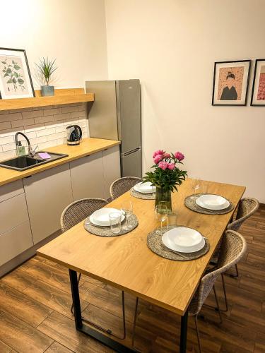 a kitchen with a wooden table with plates and flowers on it at Przytulny Apartament Mickiewicza 14/1 in Wieleń