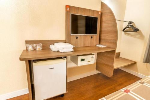 a kitchen with a microwave, sink, and refrigerator at Hotel 10 Ponta Grossa in Ponta Grossa