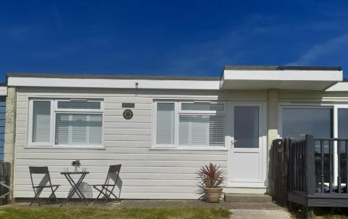 a white house with chairs in front of it at Sundown 127 Sandown Bay Holiday Centre Generous Ferry Saving! in Sandown