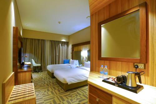 a hotel room with a bed and a flat screen tv at Al Aseel Hotel in Doha