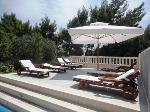 a patio with lounge chairs and an umbrella next to a pool at Villa Daniela in Bol