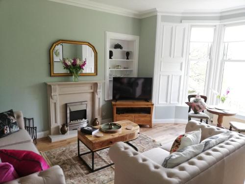 Woodburn ground-floor apartment in quiet setting in Pitlochry في بيتلوكري: غرفة معيشة مع أريكة ومدفأة