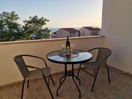 uma mesa com 2 cadeiras e uma garrafa de vinho na varanda em Apartmani Banana em Gradac