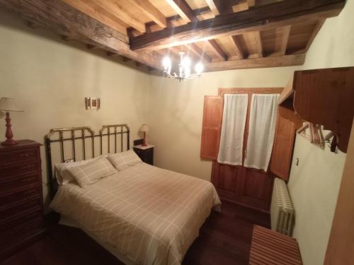 1 dormitorio con cama y lámpara de araña en Casa de Abril 2, en San Cristóbal de Valdueza