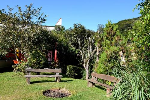 a wooden bench sitting in the grass in a park at Caminito in Santo Antônio do Pinhal