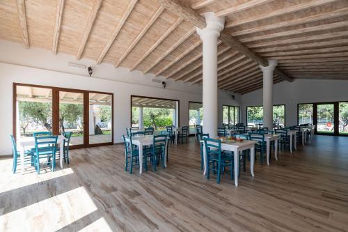 a dining room with blue chairs and tables and windows at Sisula Country Hotel & SPA in Orosei