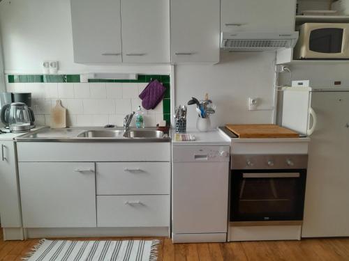 une cuisine avec des armoires blanches et un évier dans l'établissement Appartement Fort-Mahon Plage, à Fort-Mahon-Plage