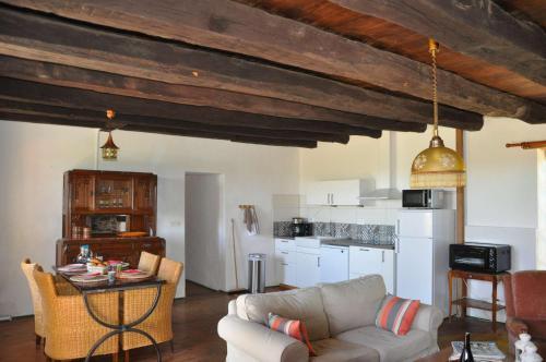 a living room with a couch and a kitchen at Gîtes du Castellare in Le Chalard