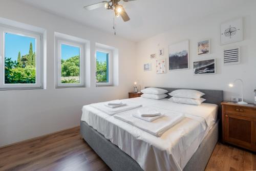 una camera bianca con un grande letto con finestre di Apartment Near Old Town, FREE PARKING & Huge Garden a Dubrovnik