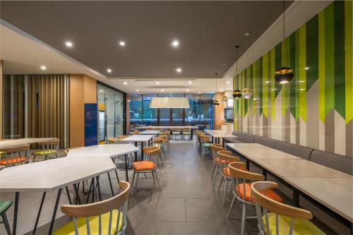 a dining room with tables and chairs and green walls at Holiday Inn Express Emei Mountain by IHG in Emeishan