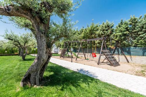 a swing set in a park next to a tree at Sisula Country Hotel & SPA in Orosei