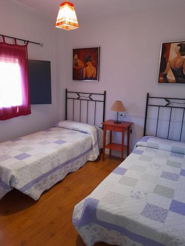 a room with two beds and a table with a lamp at Casa Rural Prado Alto,Foz Calanda in Foz-Calanda