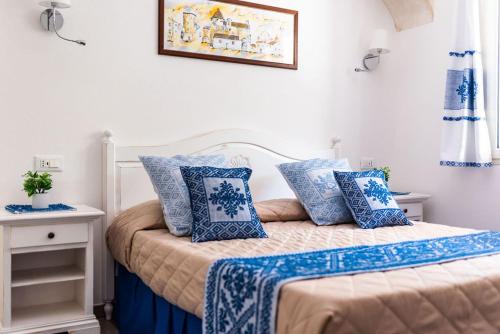 a bedroom with a bed with blue and white pillows at Sisula Country Hotel & SPA in Orosei