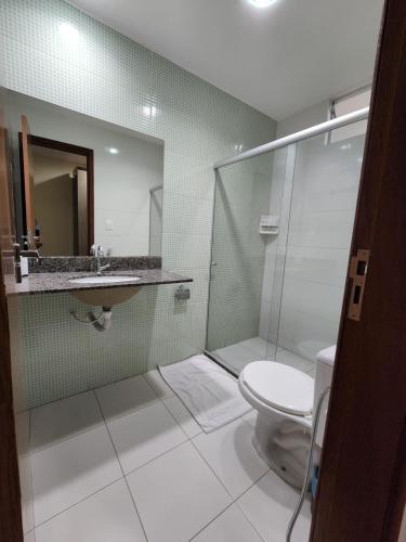 a bathroom with a shower and a toilet and a sink at Pousada Coqueiral in Aracruz