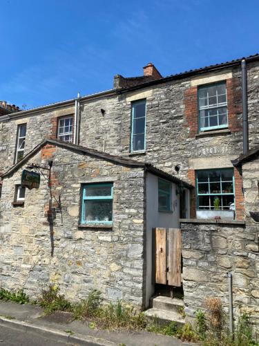 un antiguo edificio de piedra al lado de una calle en Moon in the Apple Tree, en Glastonbury