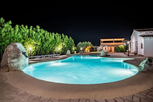 a large swimming pool in a yard at night at Sisula Country Hotel & SPA in Orosei