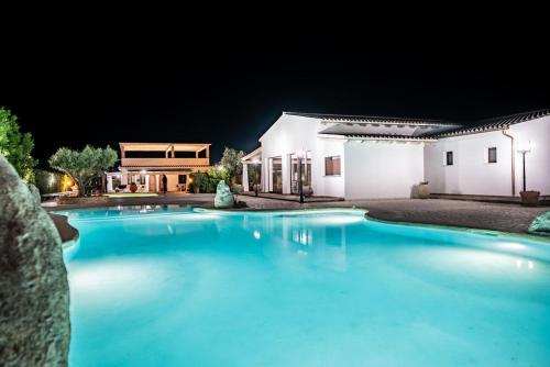 a swimming pool in front of a house at night at Sisula Country Hotel & SPA in Orosei