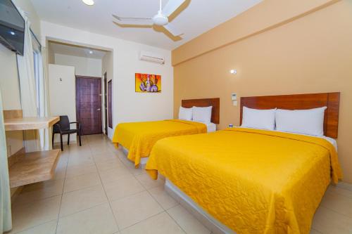 two beds in a hotel room with yellow sheets at Hotel Nonni in Santa Cruz Huatulco
