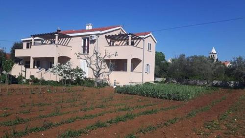 une maison sur une colline avec un champ devant elle dans l'établissement Apartmani Ratka, à Zaton