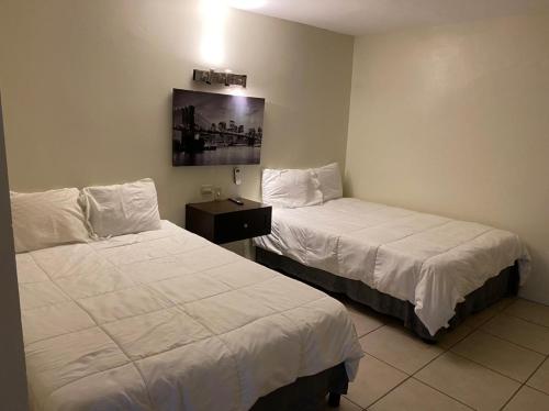 2 camas en una habitación de hotel con sábanas blancas en Yolotl Sleep Experience, en Piedras Negras
