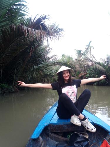 a woman sitting on a boat in the water at Nguyet Que Homestay & Tours in Ben Tre