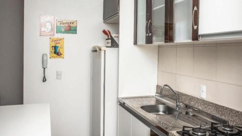 cocina con fregadero y nevera en Lindo Apartamento, amplo e confortável, Penha Santa Catarina,, en Penha