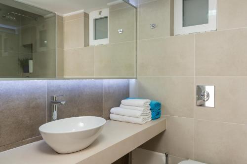 a bathroom with a sink and a mirror and towels at Hermes Beach Front in Stalos