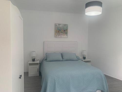 a white bedroom with a bed with a blue blanket at El Balcón de la Roca in Setenil