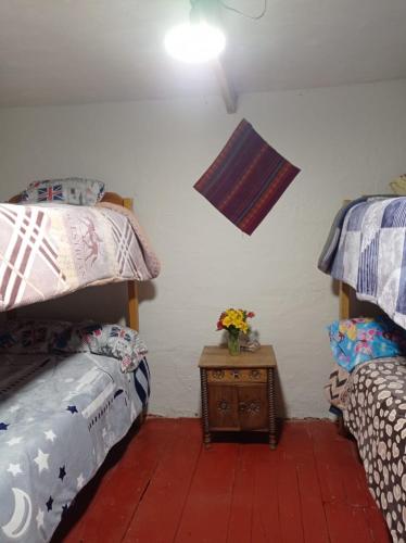 a bedroom with two bunk beds and a table with flowers at CHINA SAQRA in Cusco