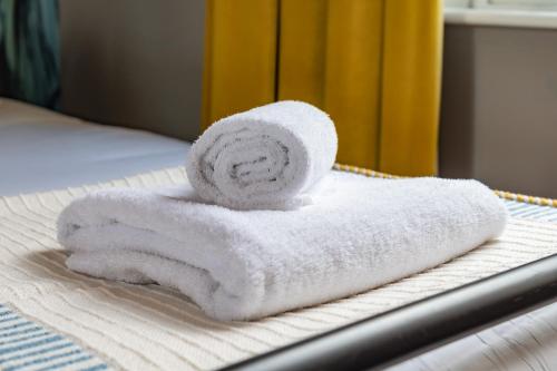 a stack of towels sitting on top of a bed at The Market House in Reading