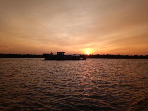 a boat on the water with the sunset in the background at Nguyet Que Homestay & Tours in Ben Tre