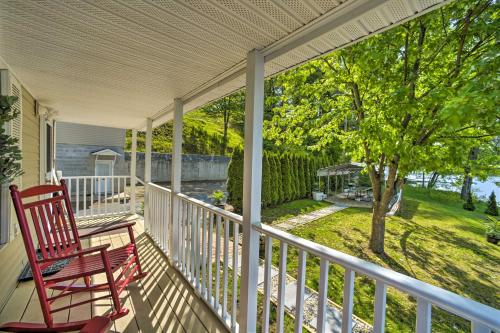 a porch with a red rocking chair and a tree at Lake Luzerne Home with Fire Pit on Hudson River in Lake Luzerne