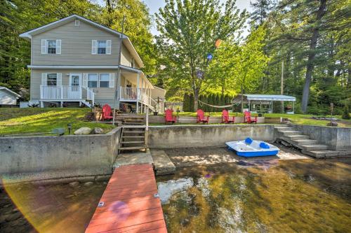 a house and a blue boat in the water at Lake Luzerne Home with Fire Pit on Hudson River in Lake Luzerne