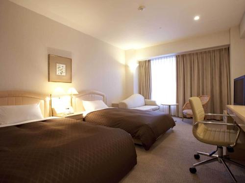 um quarto de hotel com duas camas e uma secretária em Rembrandt Hotel Oita em Oita