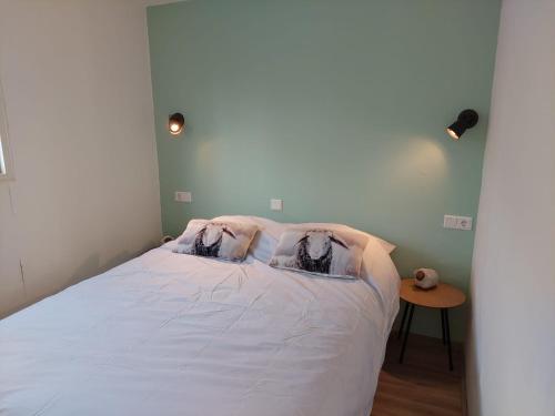 Un dormitorio con una cama blanca con dos personas. en Erfgoed de Boemerang - Chalet Schaap, en Meppen