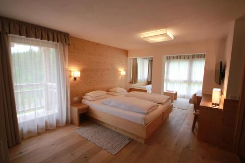 a bedroom with a large bed and two windows at Hotel Gran Paradiso in San Cassiano