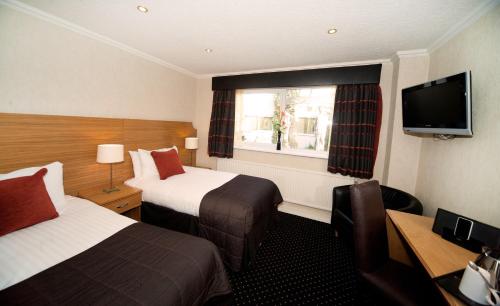 a hotel room with two beds and a television at Warrington Fir Grove Hotel, Sure Hotel Collection by BW in Warrington